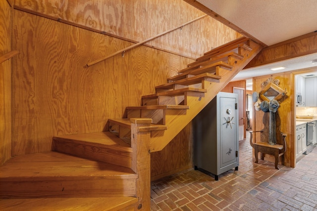 stairs featuring brick floor and wooden walls