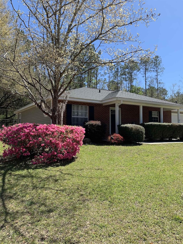 single story home with brick siding, an attached garage, and a front lawn