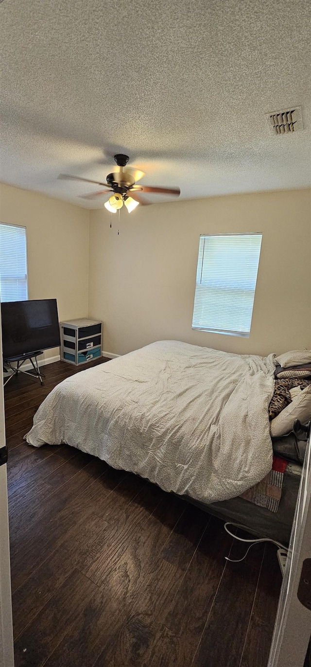 bedroom featuring wood finished floors, a textured ceiling, ceiling fan, and visible vents