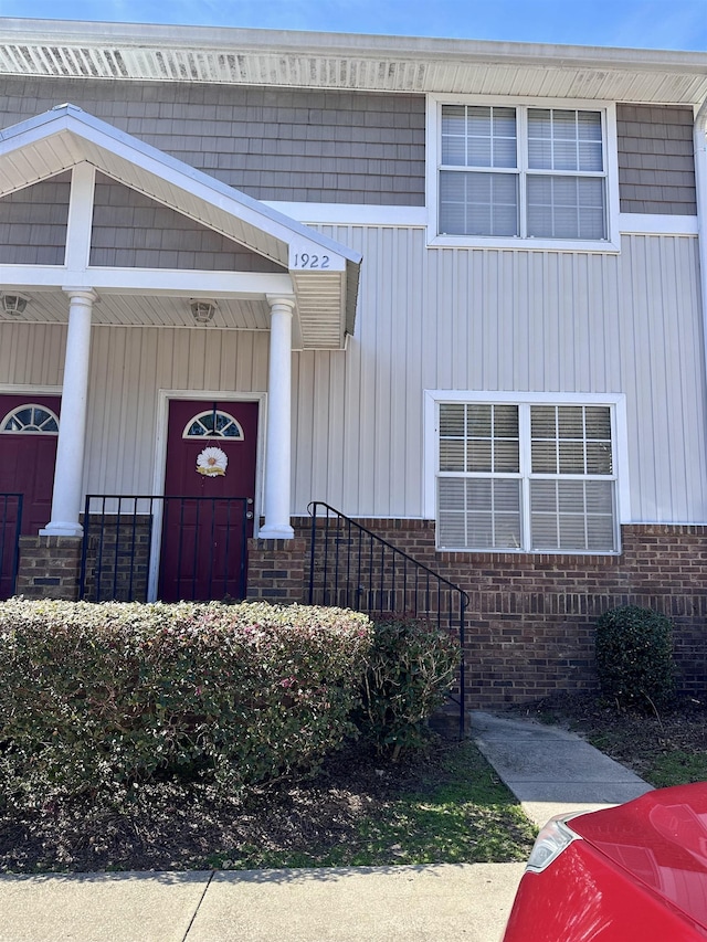 entrance to property featuring covered porch and brick siding