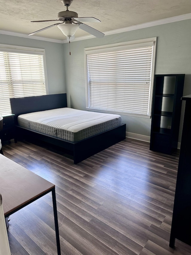 unfurnished bedroom with a textured ceiling, a ceiling fan, baseboards, ornamental molding, and dark wood finished floors