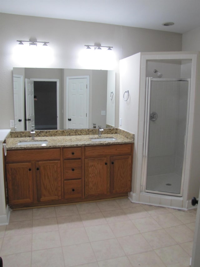 full bathroom with double vanity, a stall shower, and a sink