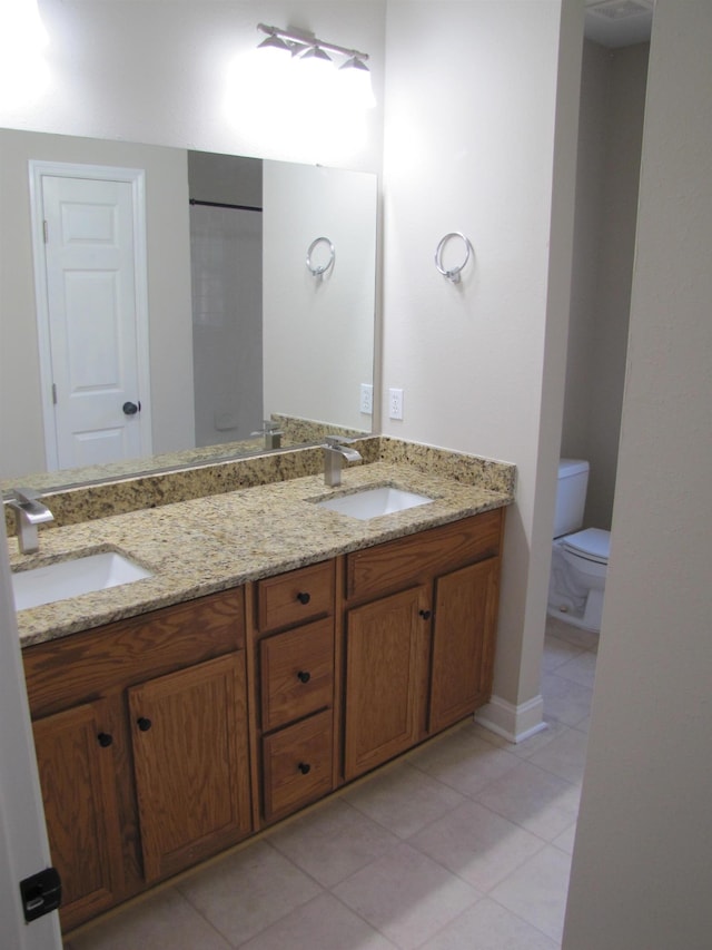 full bath with tile patterned flooring, double vanity, toilet, and a sink