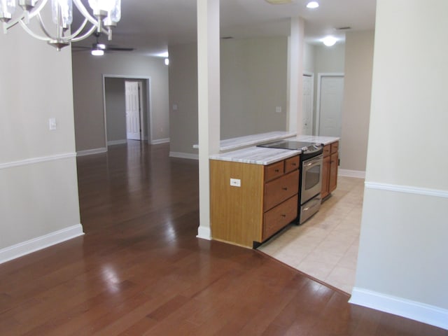 kitchen featuring electric stove, brown cabinetry, a chandelier, light wood-type flooring, and light countertops