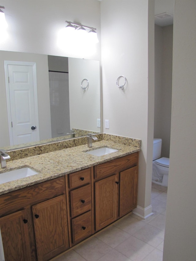 bathroom with double vanity, tile patterned floors, toilet, and a sink