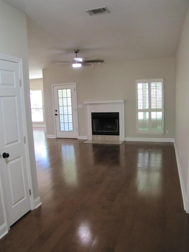 unfurnished living room featuring ceiling fan, baseboards, dark wood-style floors, and visible vents