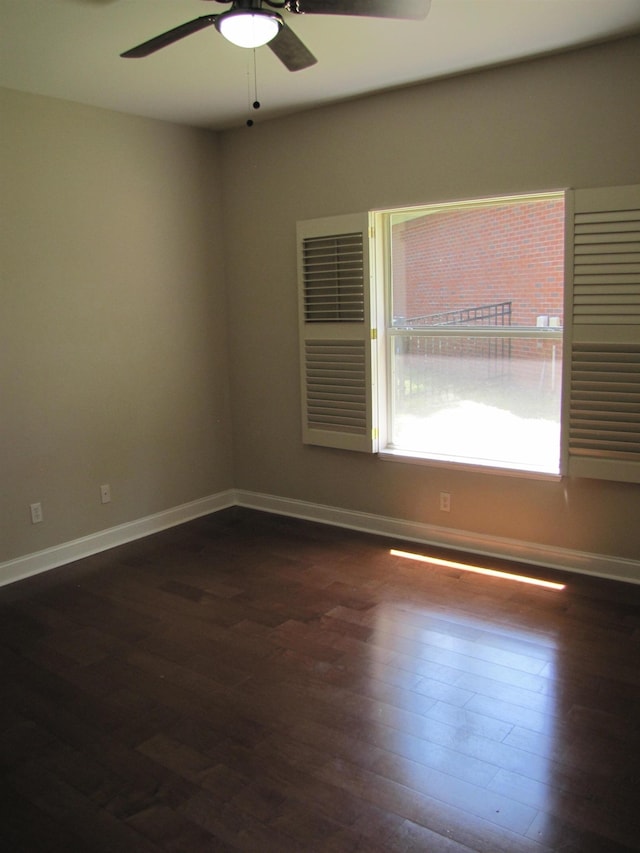 spare room featuring dark wood finished floors, baseboards, and ceiling fan