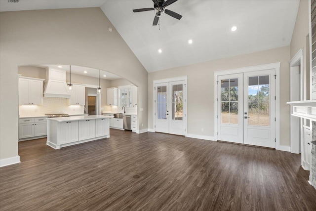 unfurnished living room featuring high vaulted ceiling, french doors, sink, dark hardwood / wood-style floors, and ceiling fan