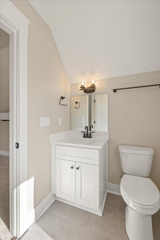 bathroom with tile patterned flooring, vanity, toilet, and lofted ceiling