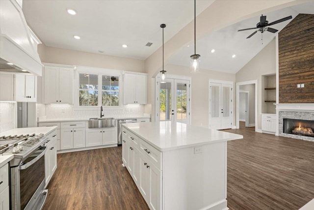 kitchen with a center island, tasteful backsplash, a stone fireplace, white cabinets, and custom range hood