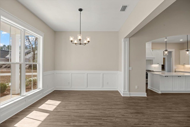 unfurnished dining area featuring dark hardwood / wood-style floors and a chandelier