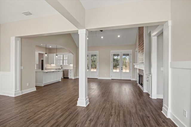 unfurnished living room featuring vaulted ceiling, dark wood-type flooring, and french doors