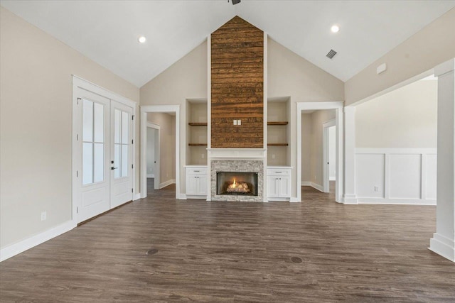 unfurnished living room with dark wood-type flooring, french doors, vaulted ceiling, built in shelves, and a fireplace