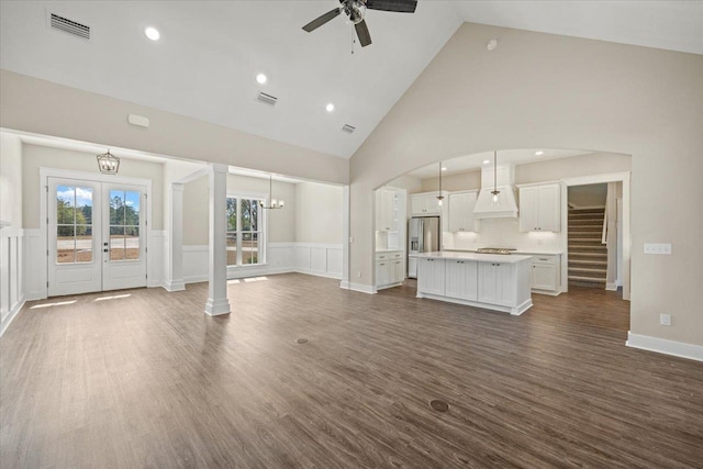 unfurnished living room featuring dark hardwood / wood-style flooring, french doors, high vaulted ceiling, and ceiling fan with notable chandelier