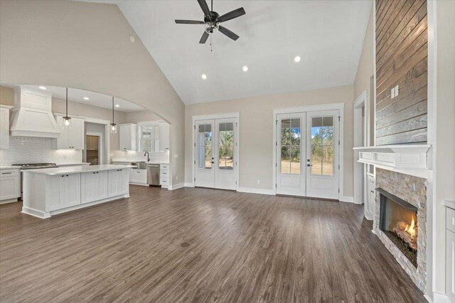 unfurnished living room with french doors, dark hardwood / wood-style flooring, high vaulted ceiling, and ceiling fan