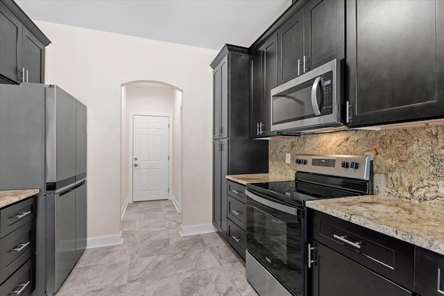 kitchen featuring stainless steel appliances, light stone countertops, and decorative backsplash