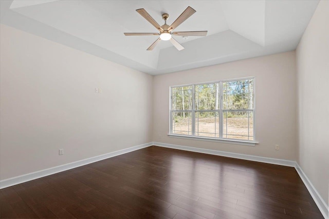 empty room featuring dark hardwood / wood-style flooring, a tray ceiling, and ceiling fan