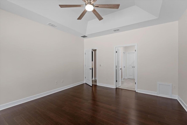 unfurnished room with ceiling fan, dark hardwood / wood-style floors, and a raised ceiling