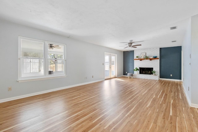 unfurnished living room with a fireplace, french doors, ceiling fan, and light hardwood / wood-style flooring