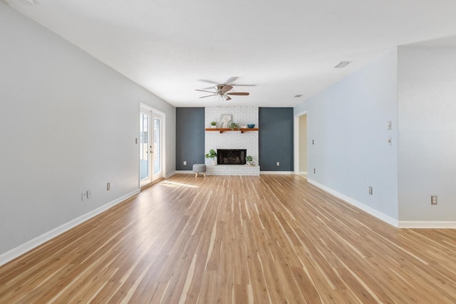 unfurnished living room with a fireplace, ceiling fan, light hardwood / wood-style floors, and french doors