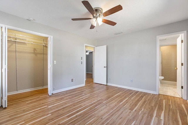 unfurnished bedroom with light wood-type flooring, a closet, ensuite bathroom, and ceiling fan