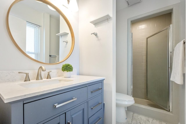 bathroom featuring vanity, a shower with shower door, and toilet