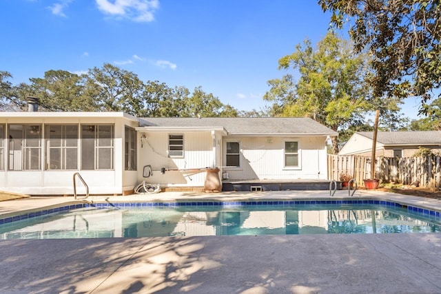 back of property with a sunroom and a fenced in pool