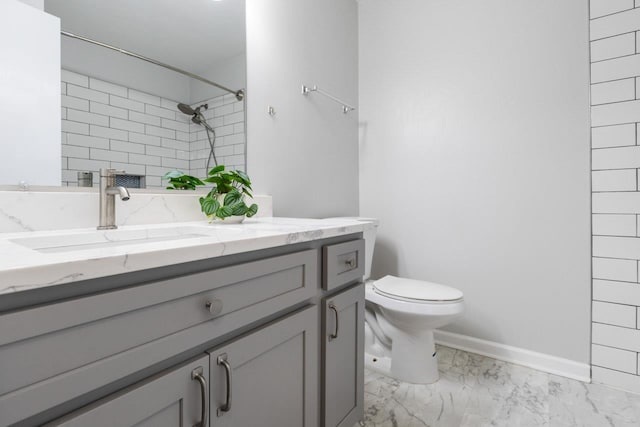 bathroom featuring a tile shower, vanity, and toilet