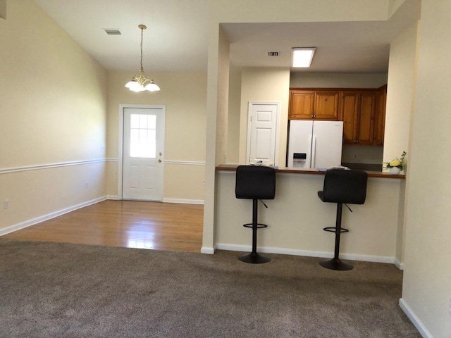 325 Chastain Ln, Tallahassee, FL 32305 - kitchen featuring a kitchen bar, carpet floors, visible vents, white fridge with ice dispenser, and brown cabinets