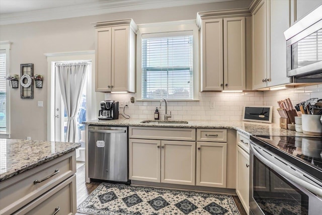 kitchen with decorative backsplash, sink, stainless steel appliances, and cream cabinets