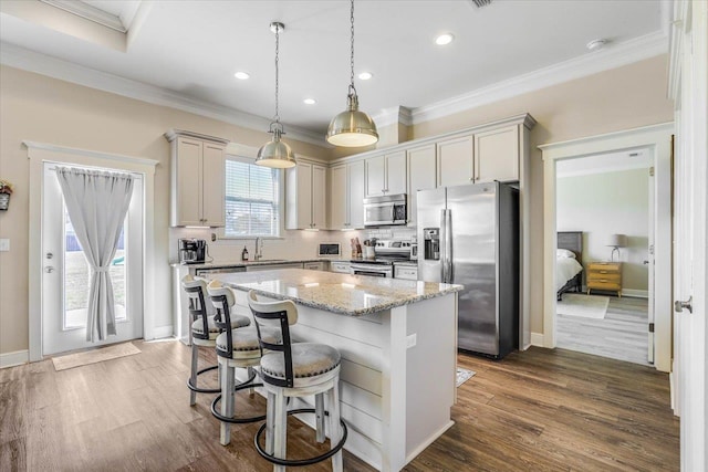 kitchen featuring light stone countertops, a kitchen island, dark wood-type flooring, stainless steel appliances, and hanging light fixtures