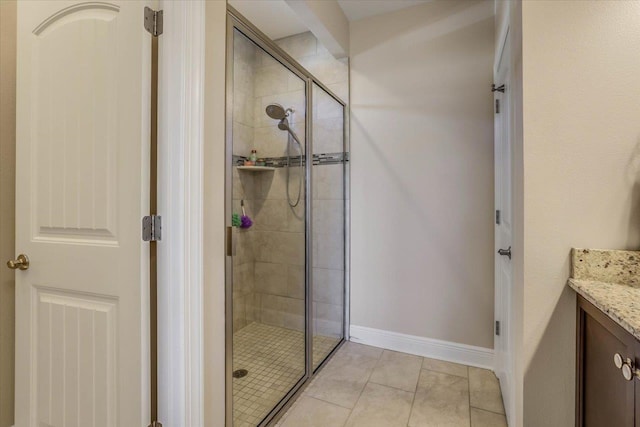 bathroom with a shower with shower door, vanity, and tile patterned floors