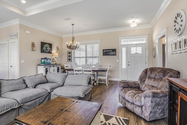 living room featuring dark wood-type flooring, a chandelier, and crown molding