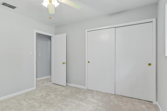 unfurnished bedroom featuring a closet, light colored carpet, and ceiling fan