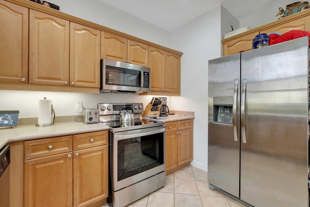 kitchen with light tile patterned floors, appliances with stainless steel finishes, and light countertops