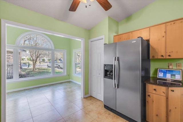 kitchen featuring light tile patterned floors, dark countertops, lofted ceiling, a textured ceiling, and stainless steel fridge with ice dispenser