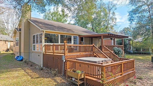 rear view of property featuring a hot tub, a chimney, and a deck