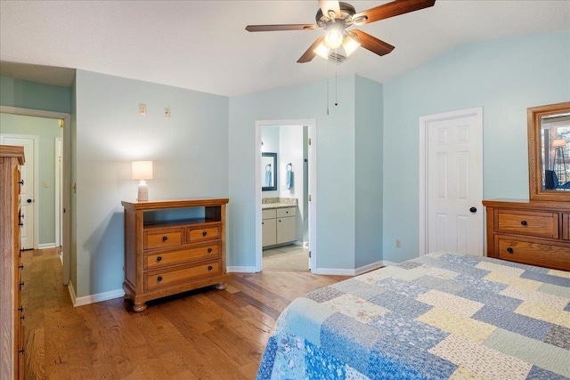 bedroom with light wood-style floors, baseboards, vaulted ceiling, and connected bathroom