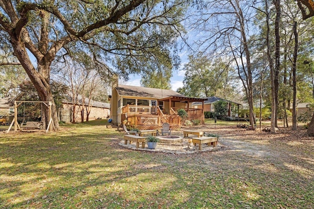 rear view of property with a fire pit, a lawn, and a wooden deck