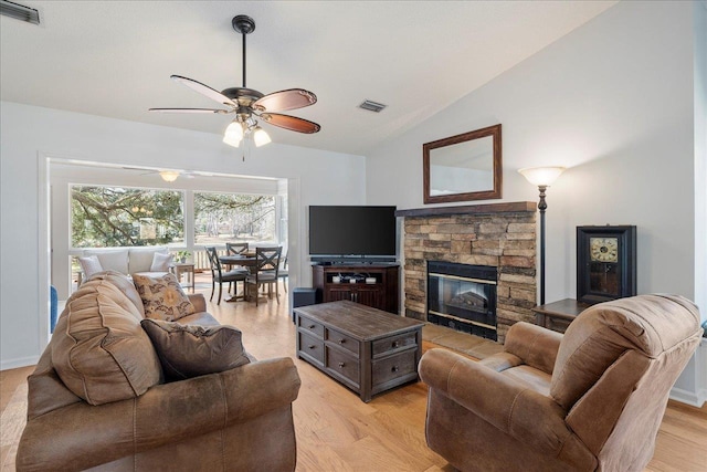 living room featuring light wood-style floors, a fireplace, visible vents, and vaulted ceiling