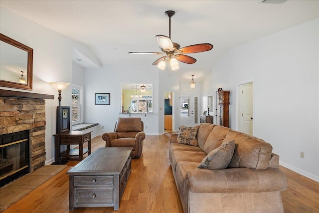 living area with lofted ceiling, light wood finished floors, a fireplace, and baseboards