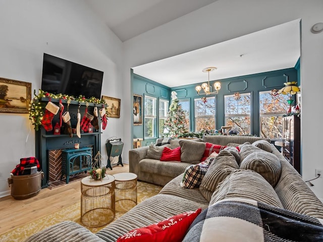 living room featuring a fireplace, hardwood / wood-style floors, vaulted ceiling, and an inviting chandelier