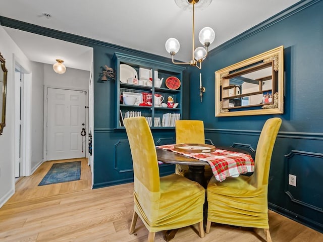 dining area with a notable chandelier, light wood-type flooring, and ornamental molding