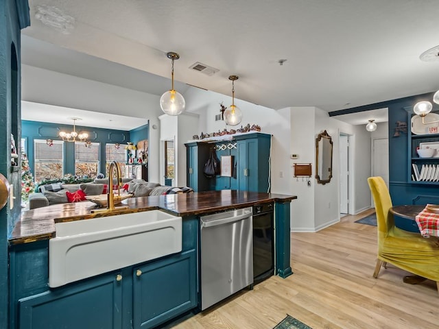 kitchen with blue cabinetry, pendant lighting, stainless steel dishwasher, and light hardwood / wood-style floors