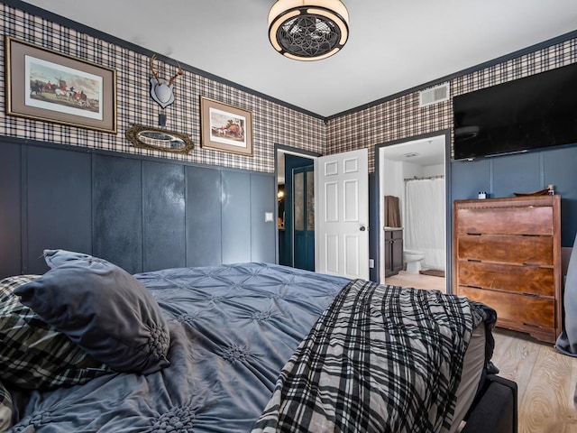 bedroom with light wood-type flooring and ensuite bath