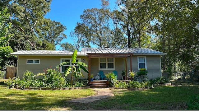 view of front of property with metal roof, a front lawn, a standing seam roof, and fence