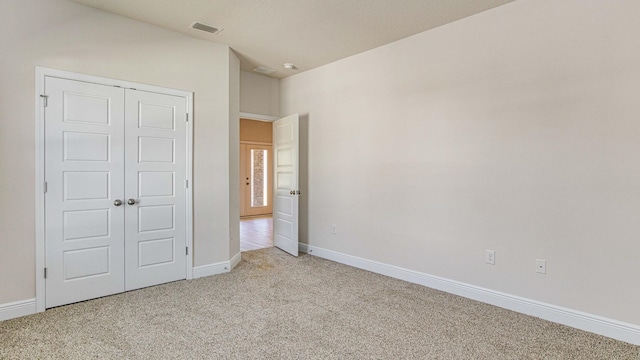 unfurnished bedroom with a closet and light colored carpet