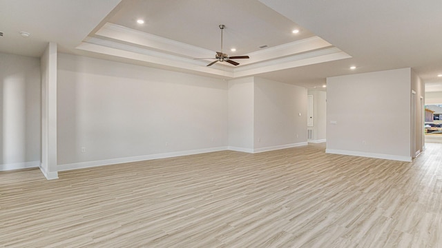 unfurnished living room with ceiling fan, light wood-type flooring, a tray ceiling, and ornamental molding