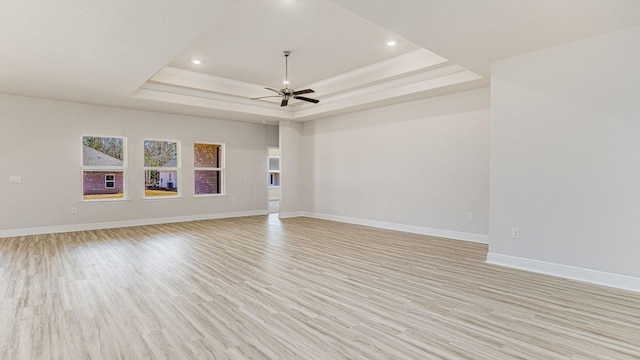 unfurnished room with light hardwood / wood-style floors, ceiling fan, and a tray ceiling