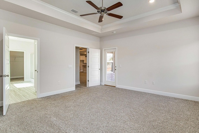 unfurnished bedroom with ceiling fan, a tray ceiling, crown molding, and a spacious closet